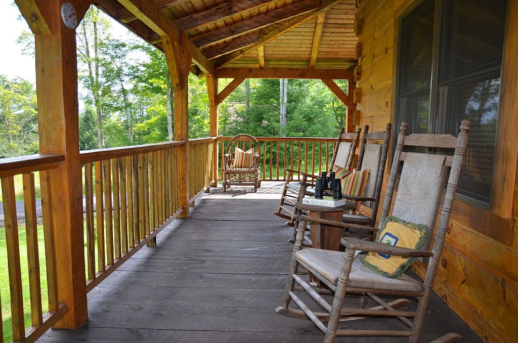 Deck of the lake house with rocking chairs, table, and binoculars for bird-watching. 