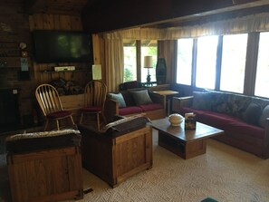 TV next to fireplace with seating overlooking the lake