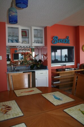 wet bar with ice maker and flat screen tv in living area