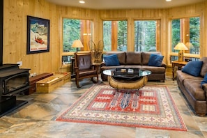 Well-appointed living room has wood burning stove, radiant heated floors.