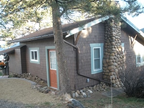 View from Drive, entrance into Living Room & view of exterior stone fireplace. 