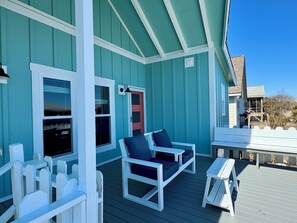 Oversized front porch with painted deck, loveseat, bench seats, & sliding gate