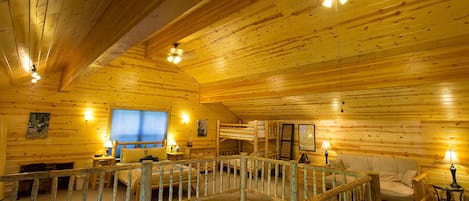 The loft, with a queen size bed, twin bunk beds, futon, desk and library.