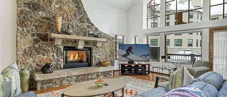 Living room with fireplace, giant TV, huge vaulted ceilings, big picture windows