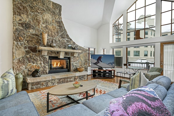 Living room with fireplace, giant TV, huge vaulted ceilings, big picture windows