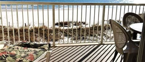 View from gulf-front balcony with chaise lounge and outdoor dining