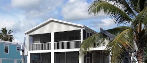 Canal view of home with open deck and enclosed upper & lower lanai