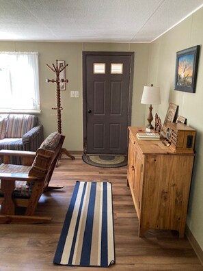 Entryway into Living Room; Cabinet containing books and board games; radio