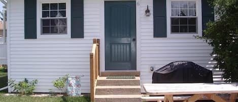 The front of Rose Wind Cottage with gas grill and picnic table on concrete pad.