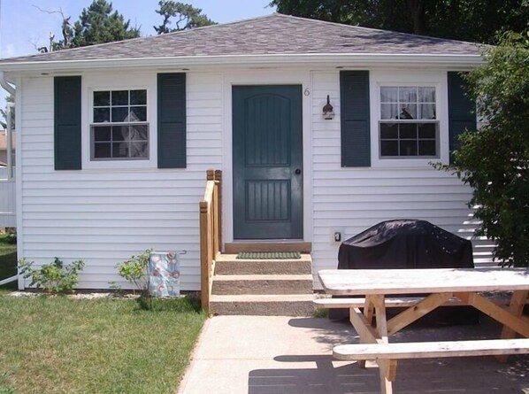 The front of Rose Wind Cottage with gas grill and picnic table on concrete pad.