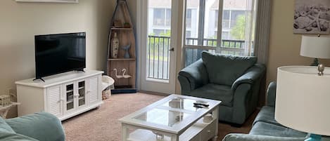 Living room with pull out couch, love seat, chair, TV, and a view of the lake. 