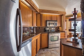 The fully stocked kitchen has cherry wood cabinets and granite counter tops.