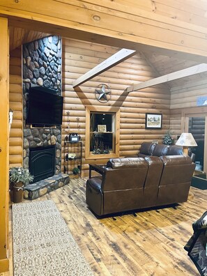 updated living room with 2 new reclining sofa's, electric fireplace, & smart tv.