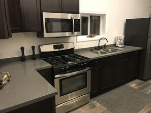 Kitchen with pots, pans, plates, glasses and utensils available.