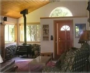 Entry to living room with woodburning fireplace and wide-screened curved TV