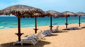 Palapas on the beach in front of pool deck. 