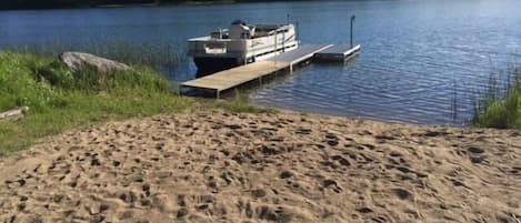 Private sandy beach with swimming area, pontoon, dock, raft, and beach toys