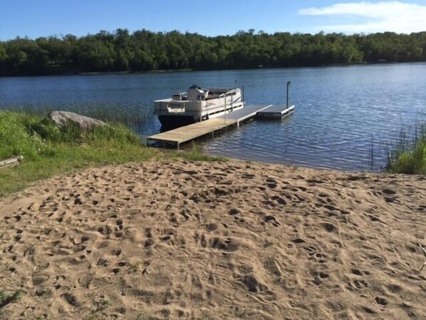 Private sandy beach with swimming area, pontoon, dock, raft, and beach toys