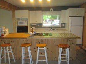 Kitchen with stove, microwave, fridge, oven, kettle, coffee pot.