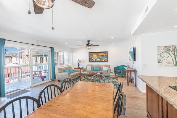 Main living and dining area with sliding glass doors to front ocean view balcony. Ceiling fans throughout.
                