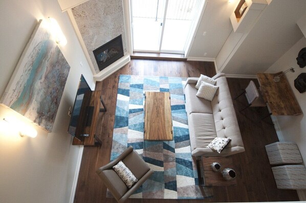 Overhead view of the living room, featuring a stunning granite fireplace and a large framed TV. 