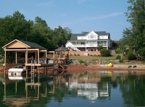 A view of the home from the lake. A private cove with a dock, gazebo and toys.