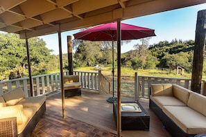 patio area with bbq and seating looking towards the grassy backyard and views