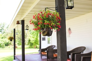 Front porch with view of barn yard, windmill and flower bed