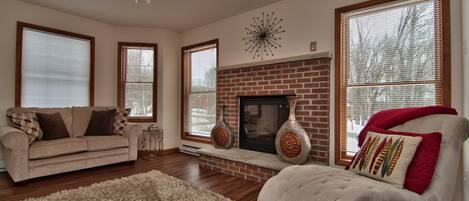 Relaxing room, red brick gas fireplace, couches, lounge chair, lots of light