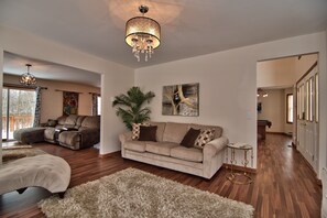 Couch and chaise lounge chair in fireplace room with open entrance to TV room
