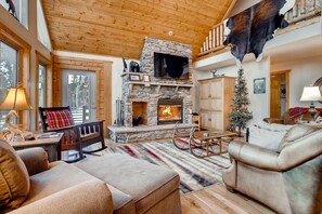 This is the main level great room with vaulted ceilings and a huge stone wood-burning fireplace.