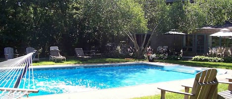 Pool and view of main house, multiple lounge chairs, Adirondacks, and hammock