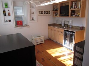 Lower level TV room, wine fridge and bar/sink with futon couch