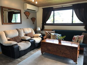 The living rooms includes a couch, a futon couch, a coffee table and tv. 
