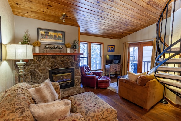 Living room with gas fireplace, smart TV with cable, and balcony.