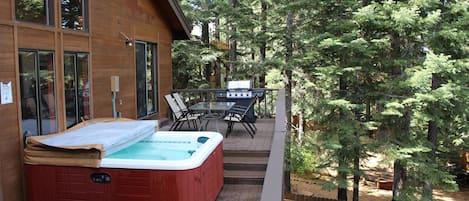 Back deck with a large Hot Tub, table with chairs and a BBQ