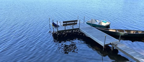 Beach area and dock complete with dock bench, canoe, and paddle boat. 