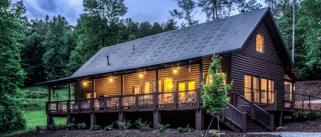 Full width of cabin screen porch with huge vaulted ceilings, fans and furniture.