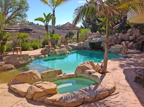 Salt water pool and hot tub with waterfall streaming over 'the grotto.'