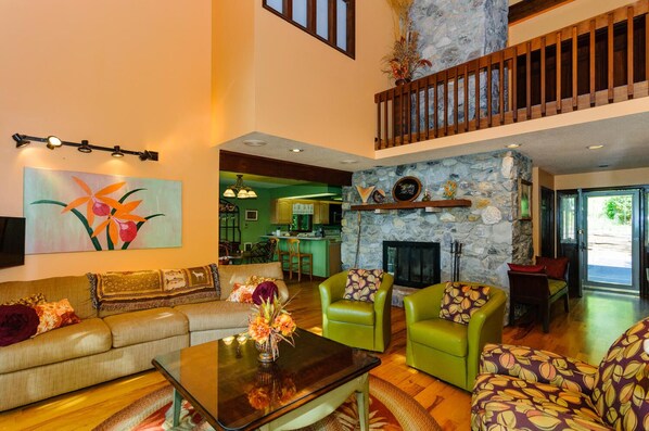 Ground floor living room with open floor plan and wood fireplace.