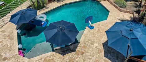 Swimming pool with baja shelf, in-pool seating, and luxurious travertine.