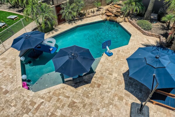 Swimming pool with baja shelf, in-pool seating, and luxurious travertine.