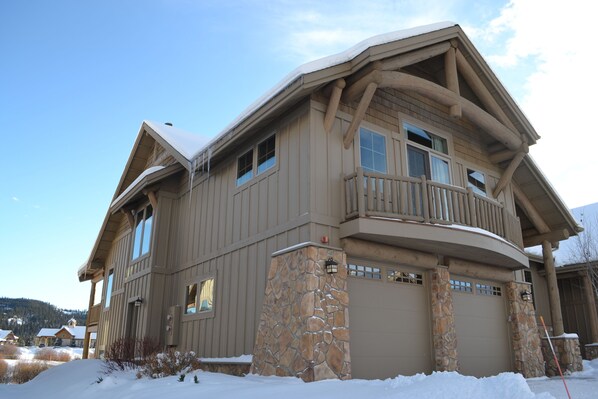 View of grand house in winter; large balcony, view of creek, mtns and meadow on other side
