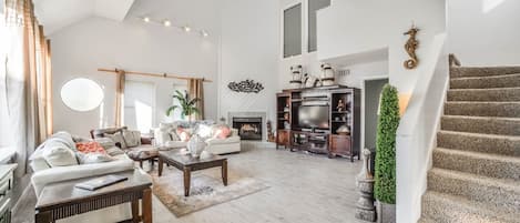 Large living room full of windows that looks out at the beach..