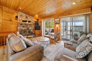 Main level living room w wood burning fireplace and panoramic views of the lake