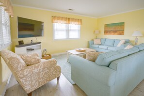 Living room with 55" 4K TV+soundbar, DVD player, two large sofas and chair.