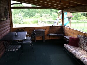 Rear covered porch that is also screene in and carpeted.