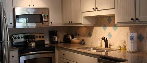 The kitchen w/ custom cabinets , granite, and stainless appliances 