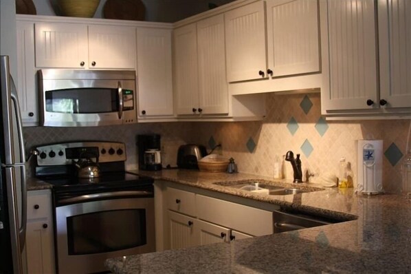 The kitchen w/ custom cabinets , granite, and stainless appliances 