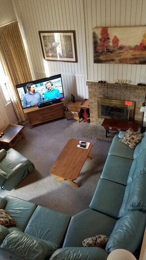 Sunken living room view from kitchen level w/ 60 inch smart tv and dvd player